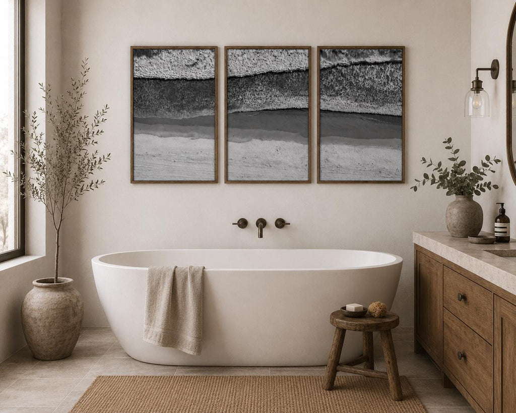 May include: A triptych of framed wall art prints featuring a black and white aerial view of ocean waves crashing onto a sandy beach. The three rectangular frames are arranged horizontally, displaying a continuous coastal landscape scene.