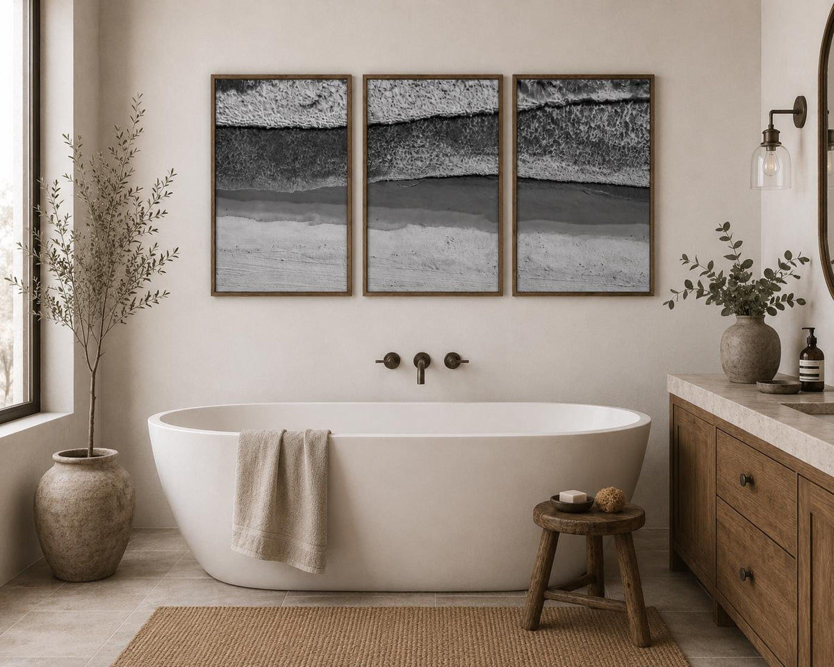May include: A triptych of framed wall art prints featuring a black and white aerial view of ocean waves crashing onto a sandy beach. The three rectangular frames are arranged horizontally, displaying a continuous coastal landscape scene.