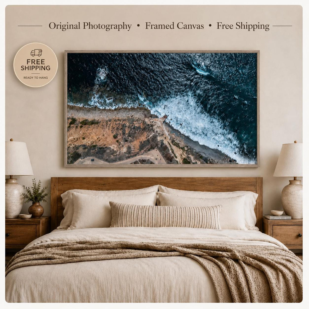 Aerial ocean coastline framed canvas wall art featuring deep blue water, crashing white waves, rocky cliffs, and a warm Oak Vintage Flair frame in a neutral bedroom.