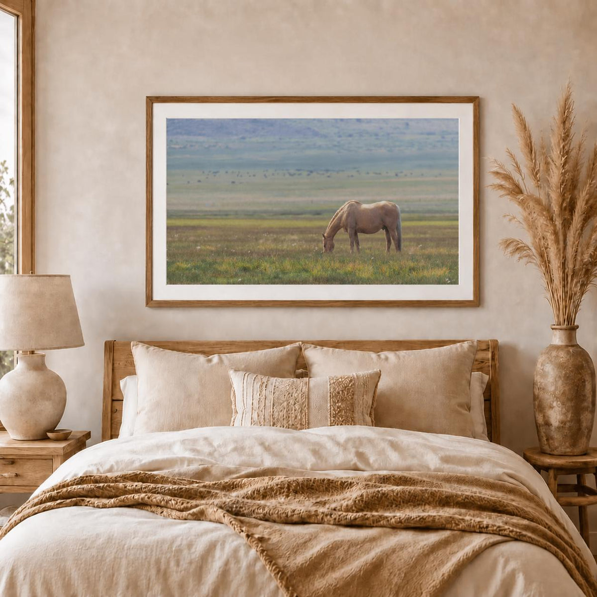 May include: A rectangular framed wall art print featuring a tan horse grazing in a vast, open green field under a soft, hazy sky. The artwork is displayed in a thin wooden frame, capturing a serene landscape scene with muted natural tones.