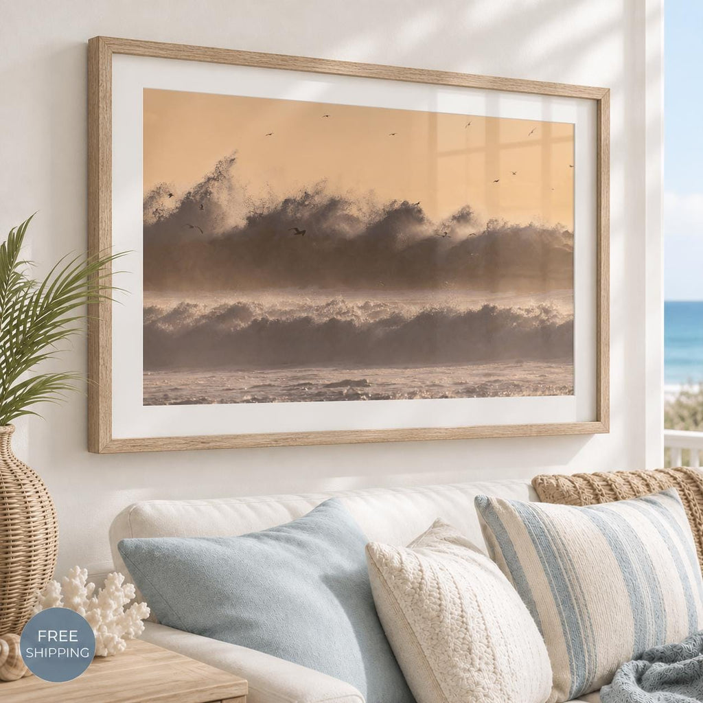 May include: A rectangular framed wall art print featuring a sepia-toned ocean scene with large crashing waves and a hazy, light orange sky. The artwork is enclosed in a light-colored wooden frame with a wide white mat border surrounding the image.