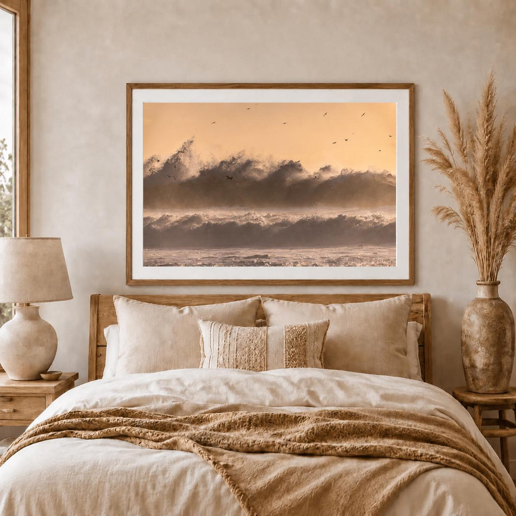 May include: A rectangular framed wall art print featuring a landscape of crashing ocean waves under a soft golden sunset sky with small birds flying in the distance. The artwork is displayed in a thin wooden frame with a white mat border.