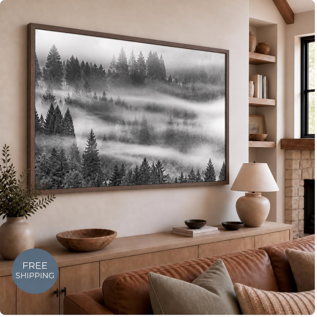 Black and white misty forest canvas in a Walnut Flair floating frame, displayed above a wooden console beside a table lamp. A brown sofa sits below. A badge reads Free Shipping.