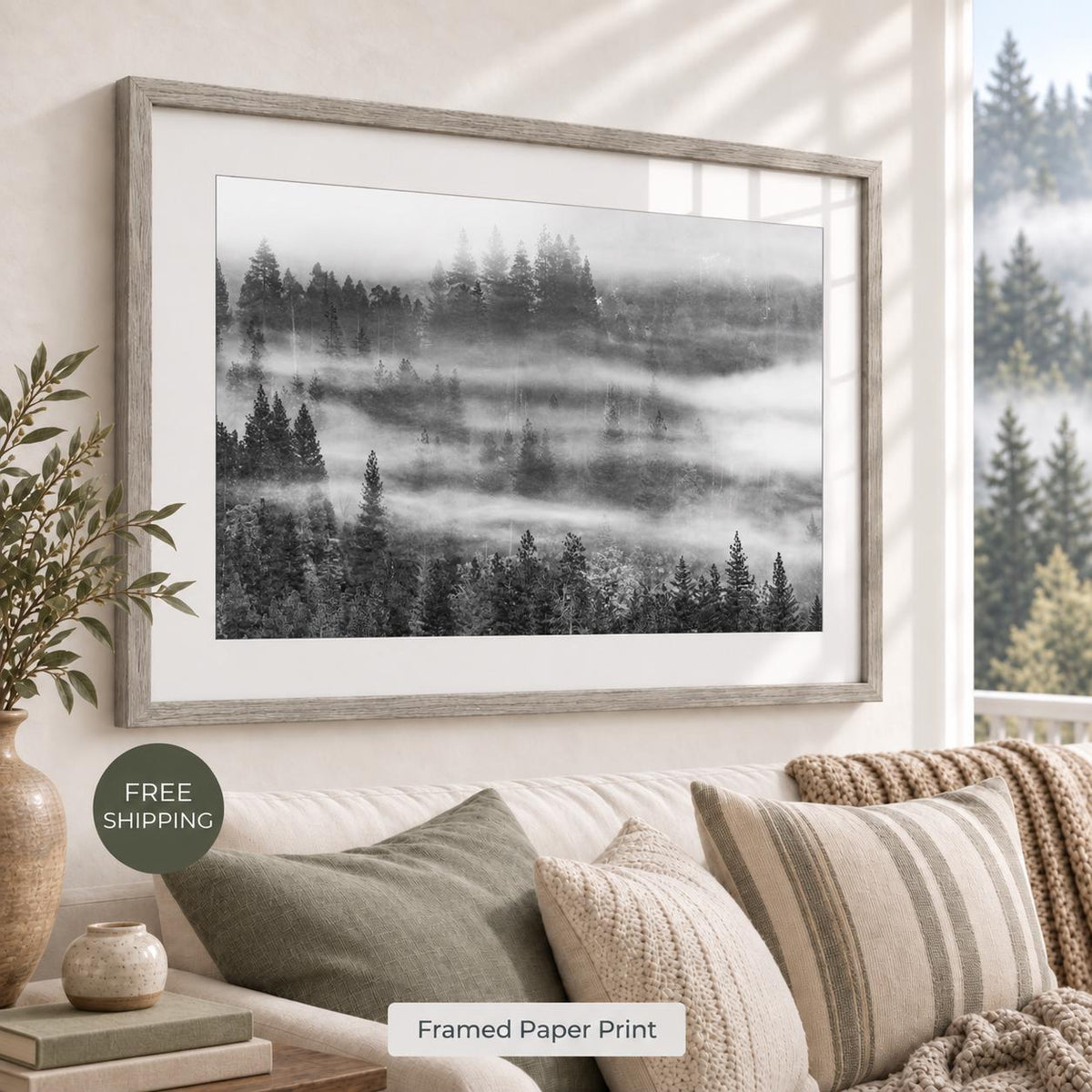 Misty evergreen forest photograph in black and white, with a white mat and weathered Oak Vintage Flair frame, displayed above a neutral sofa. Room mockup for the oak finish.