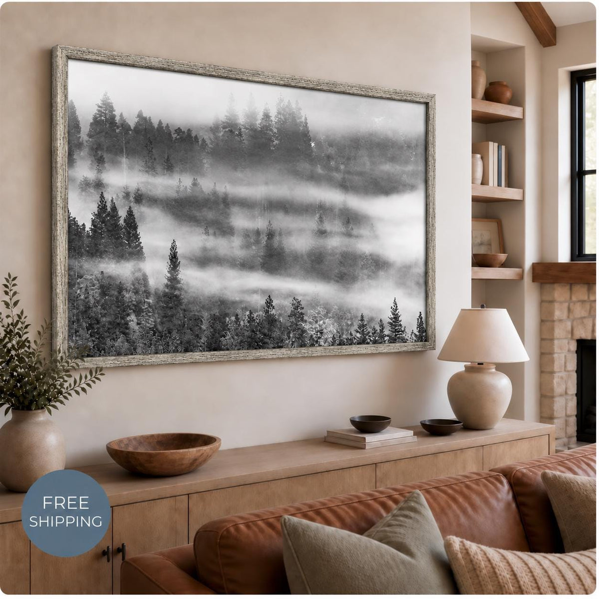 Misty forest canvas in a textured Vintage Silver floating frame, displayed above a wooden console and brown sofa. Layers of fog separate the dark trees. A badge reads Free Shipping.