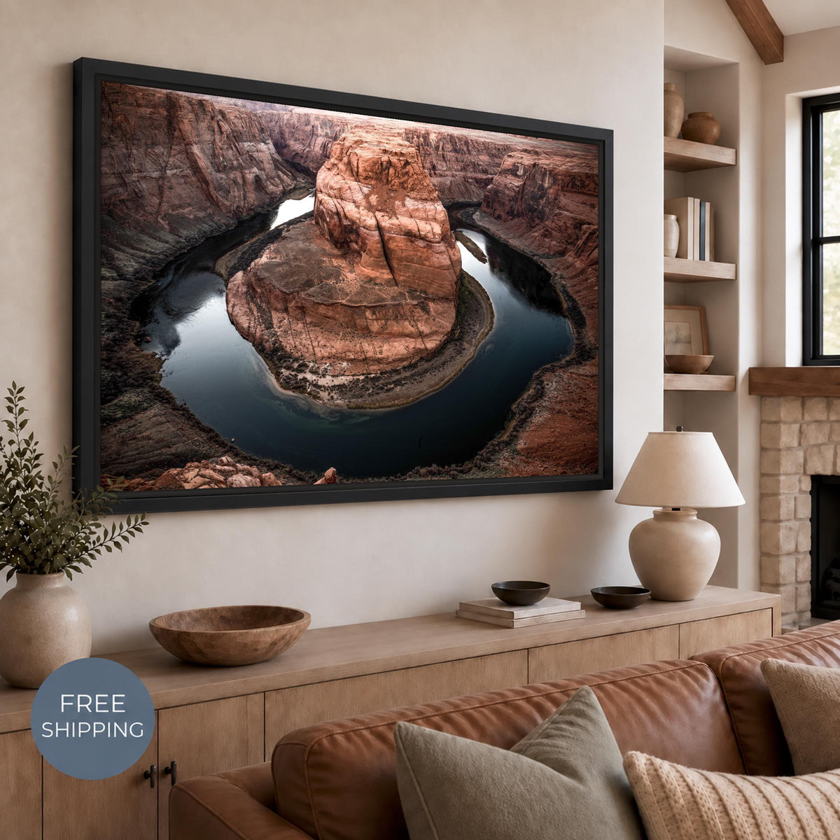 Horseshoe Bend photograph on canvas in a Black Matte floating frame, with a narrow dark gap around the canvas. Displayed above a wooden sideboard in a beige living room with a leather sofa. Free Shipping badge at lower left.