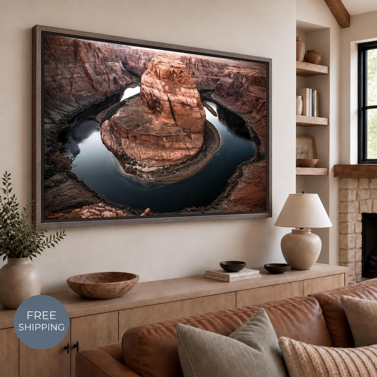 Horseshoe Bend canvas in a Walnut Flair floating frame above a wooden sideboard and brown leather sofa. Rust-colored sandstone cliffs surround the deep blue-green Colorado River. A badge reads Free Shipping.